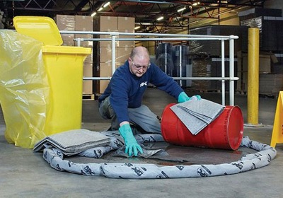 Oil spill kit with absorbent pads and safety supplies in a workshop garage