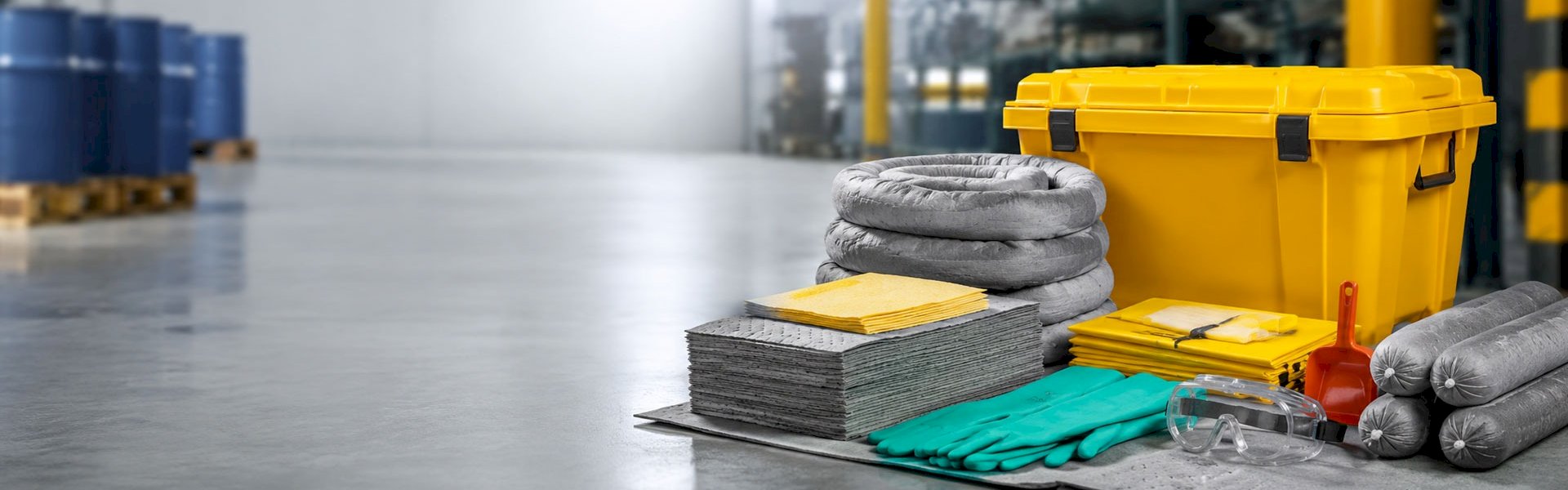 Industrial spill kit with yellow bin, absorbent pads, and gloves.